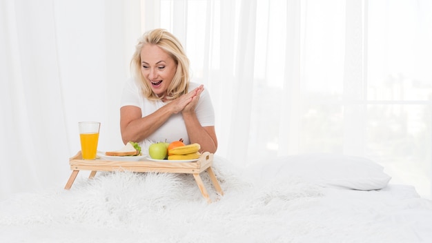 Gratis foto middelgroot schot verraste vrouw met ontbijt op bed