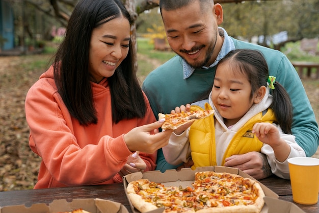 Gratis foto middelgrote familie die pizza buiten eet