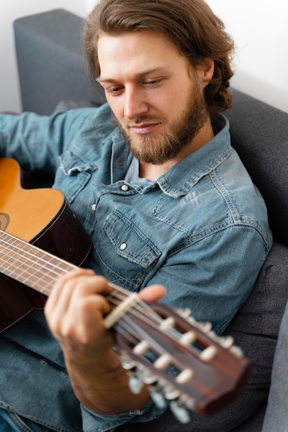 Middelgrote geschoten man die thuis gitaar speelt