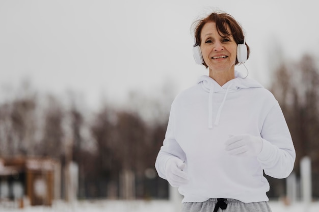 Gratis foto middelgrote geschoten vrouw die met hoofdtelefoons loopt