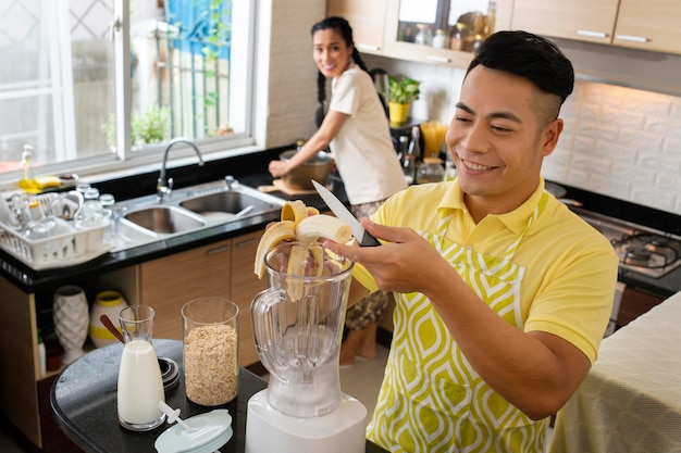 Gratis foto middelgrote man die banaan snijdt