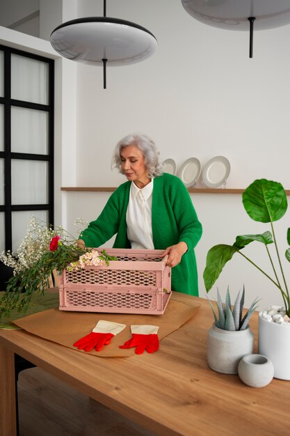 Middelgrote oude vrouw die voor planten zorgt.