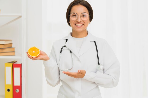 Middelgrote schot gelukkige arts die een sinaasappel steunt