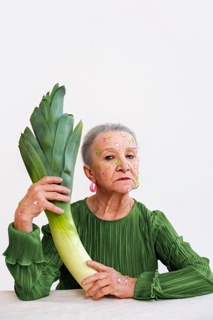 Middelgrote senior vrouw poseert met selderij.