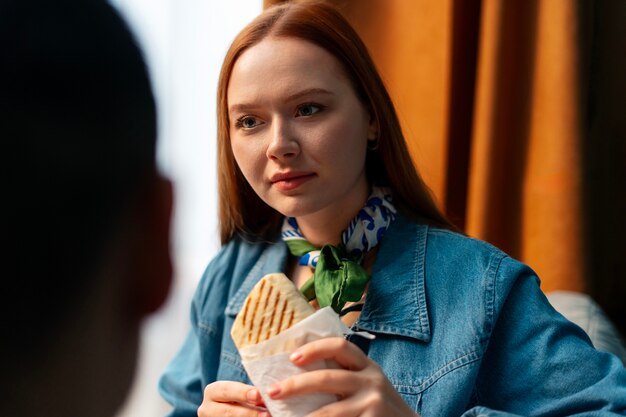 Middelgrote vrouw met een in papier gewikkeld broodje.