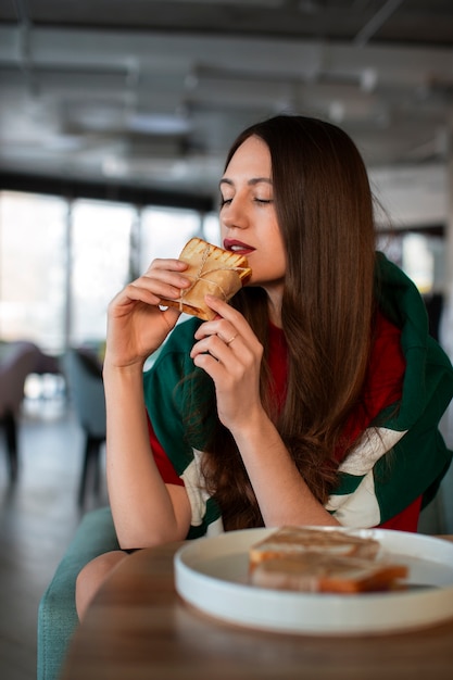 Gratis foto middelgrote vrouw met een in papier gewikkeld broodje.