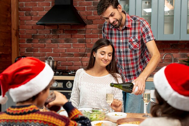 Middellange geschoten echtgenoot die champagne giet aan zijn vrouw