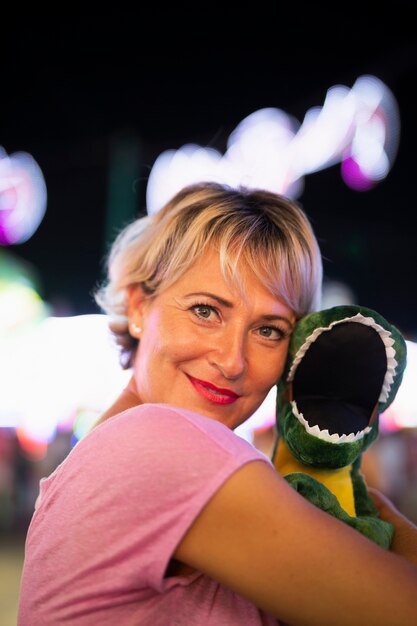 Middellange geschoten gelukkige vrouw die dinosaurusstuk speelgoed koesteren