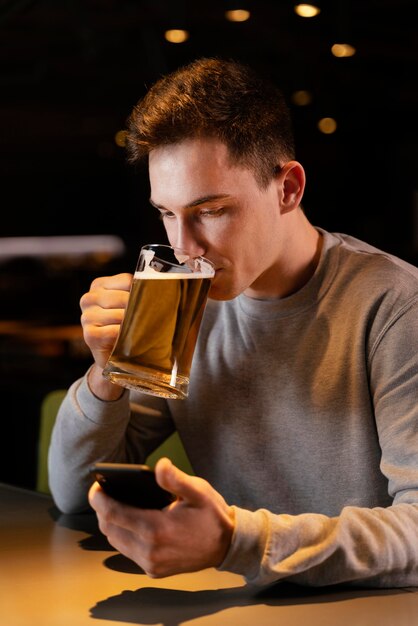 Middellange geschoten man bier drinken in de pub