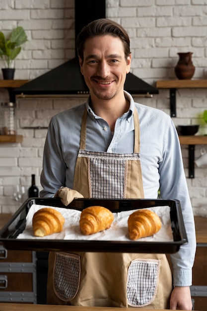 Gratis foto middellange geschoten man met een dienblad met croissants