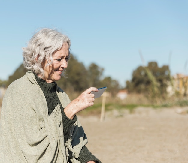 Gratis foto middellange geschoten oude vrouw met smartphone