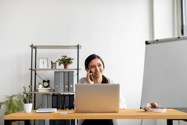 Middellange geschoten smileyvrouw die op telefoon spreekt