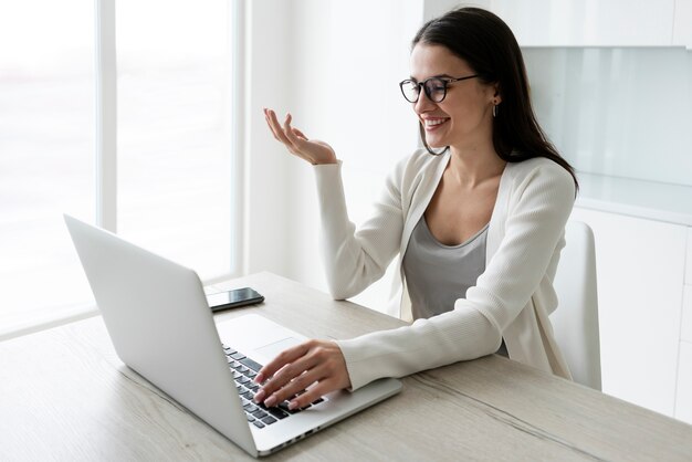 Middellange geschoten vrouw die met laptop thuis werkt