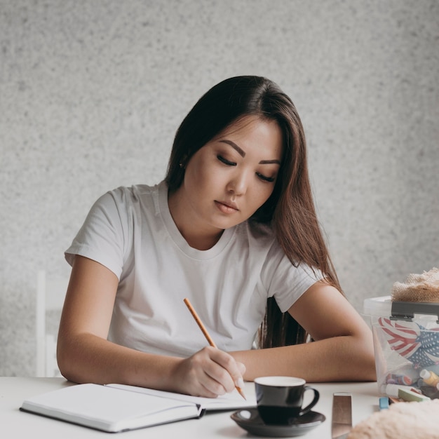 Middellange geschoten vrouw die op notitieboekje schrijft