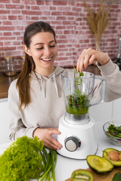 Gratis foto middellange geschoten vrouw die smoothie voorbereidt