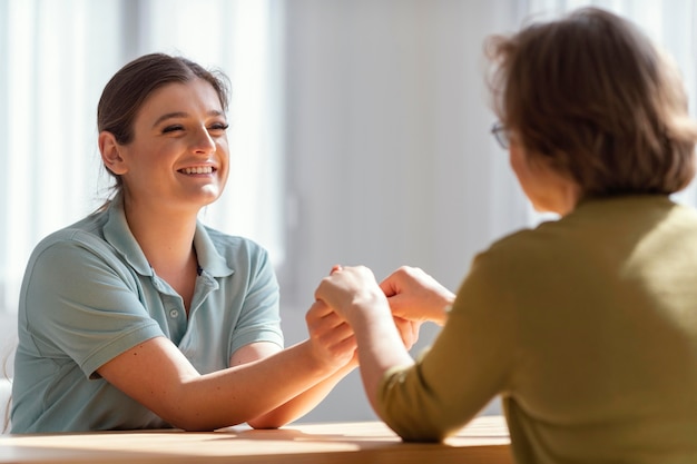 Middellange geschoten vrouwen die handen binnenshuis vasthouden