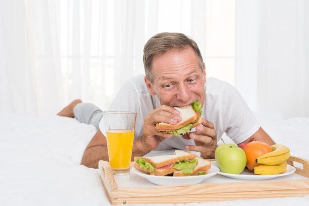 Middellange geschotene mens die ontbijt in bed heeft