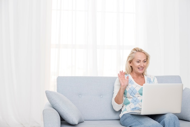 Middellange geschotene smileyvrouw met laptop het golven