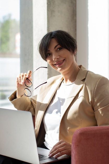 Gratis foto middellange geschotene smileyvrouw met laptop