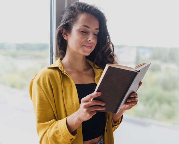 Middellange geschotene vrouw die een boek steunt