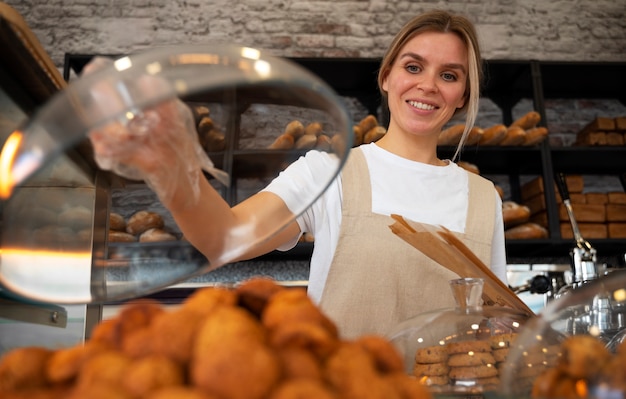Gratis foto middellange geschotene vrouw die in bakkerij werkt