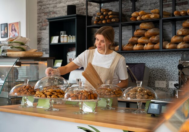 Middellange geschotene vrouw die in bakkerij werkt