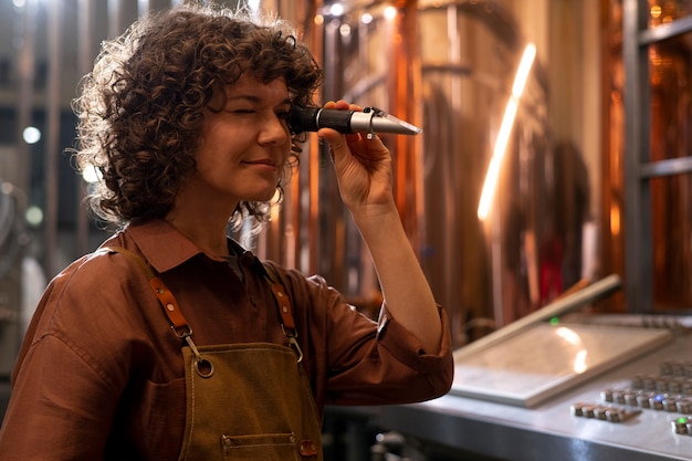 Gratis foto middellange geschotene vrouw die in bierfabriek werkt