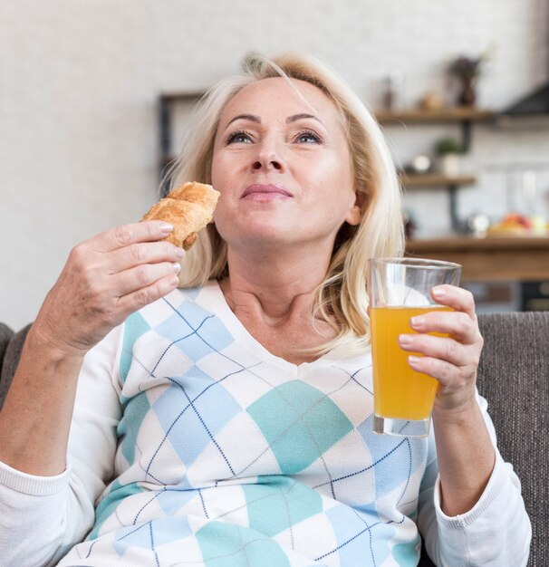 Middellange geschotene vrouw die op de bank eet