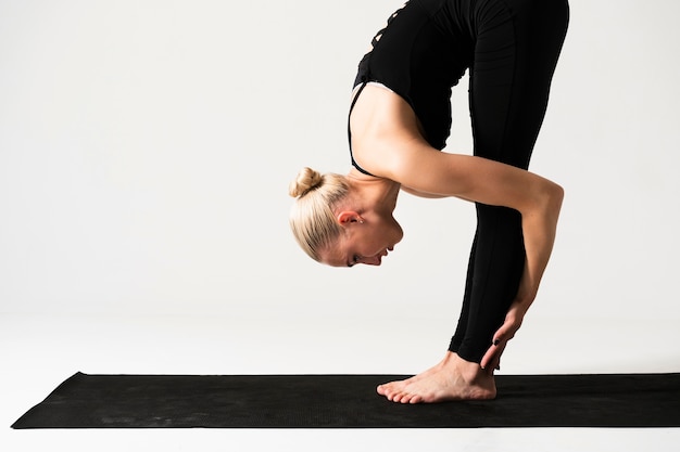 Gratis foto middellange geschotene vrouw die zich op yogamat bevindt