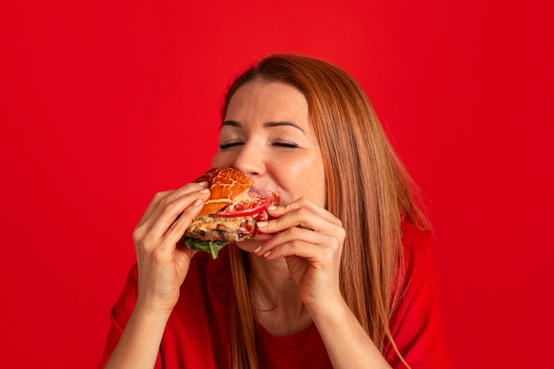 Gratis foto middellange shot jonge vrouw die hamburger eet