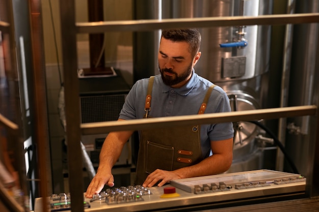 Gratis foto middellange shot man aan het werk in bierfabriek