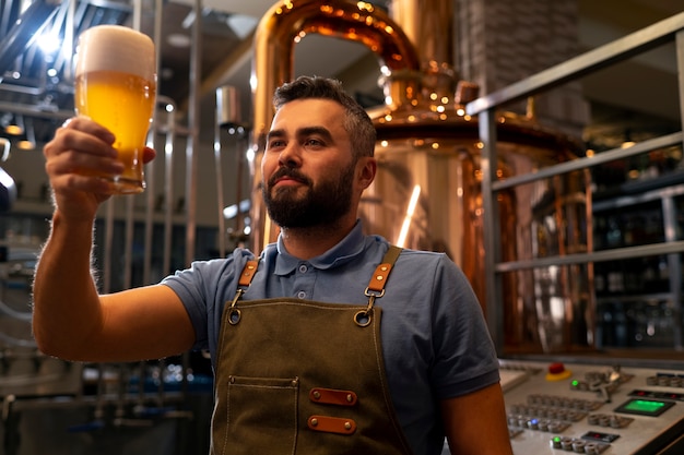 Gratis foto middellange shot man aan het werk in bierfabriek