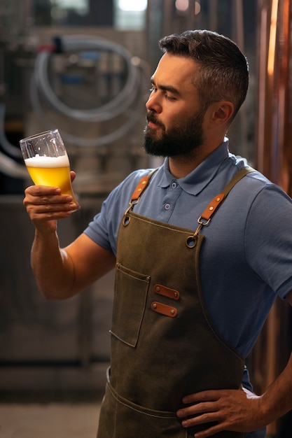 Gratis foto middellange shot man aan het werk in bierfabriek