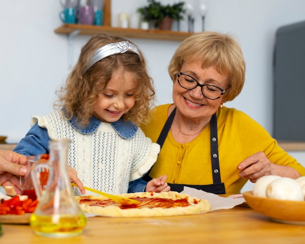 Gratis foto middellange shot oude vrouw en meisje in de keuken