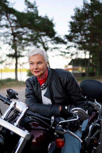 Gratis foto middellange shot senior vrouw met motorfiets