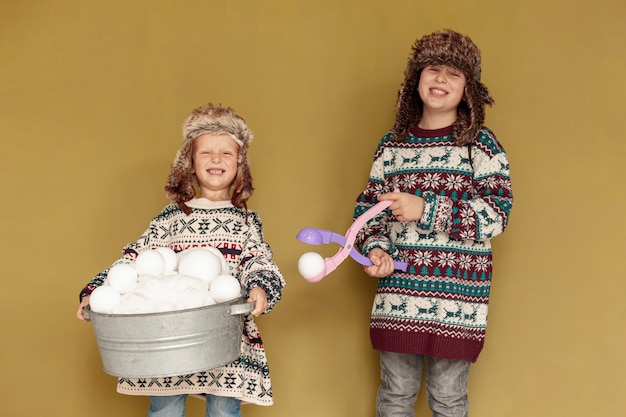 Gratis foto middellange shot smiley kinderen met sneeuwballen