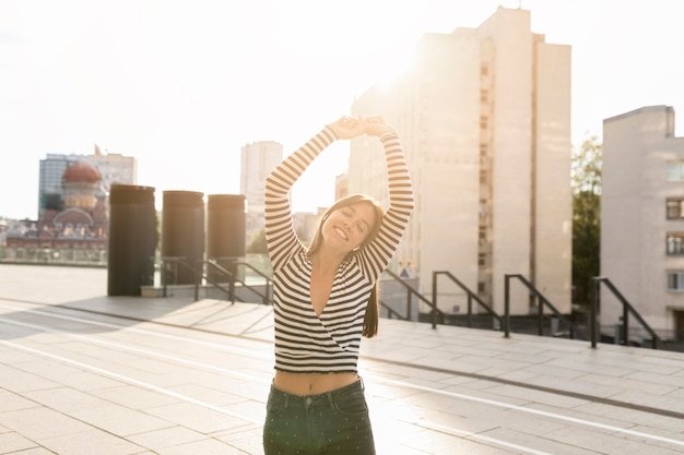 Gratis foto middellange shot smiley vrouw poseren op zonlicht