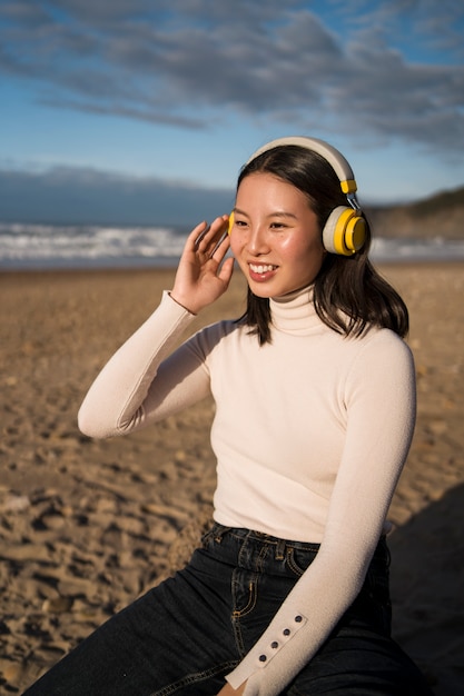 Gratis foto middellange shot smiley vrouw zittend op het strand