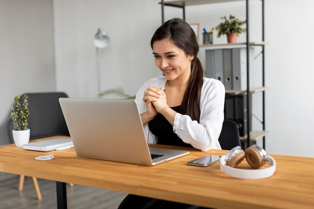 Middellange shot smileyvrouw videoconferentie