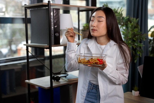 Gratis foto middellange shot vrouw die aziatisch eten eet