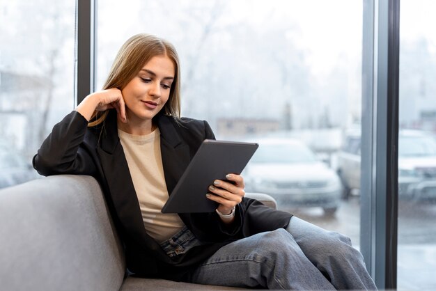 Middellange shot vrouw die digitaal tijdschrift leest