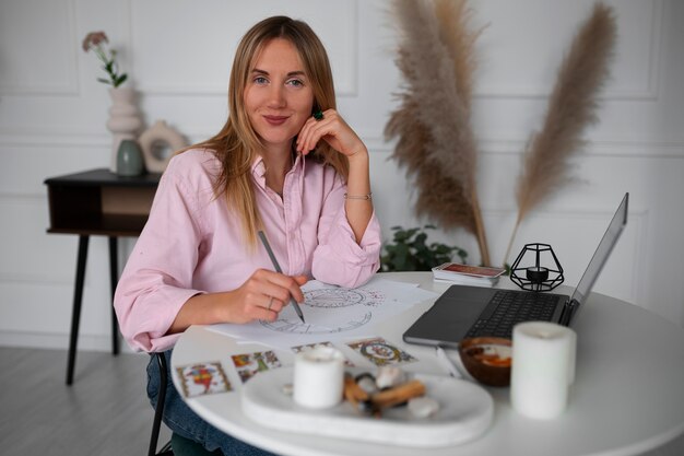 Gratis foto middellange shot vrouw die tarot leest met laptop