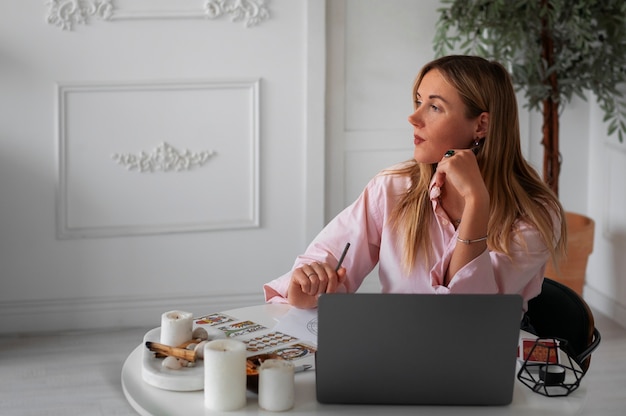 Gratis foto middellange shot vrouw die tarot leest met laptop