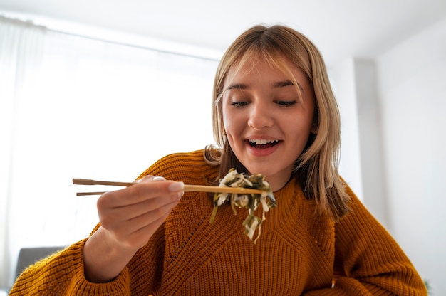 Gratis foto middellange shot vrouw die thuis eet