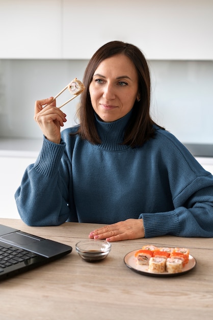 Gratis foto middellange shot vrouw die thuis sushi eet