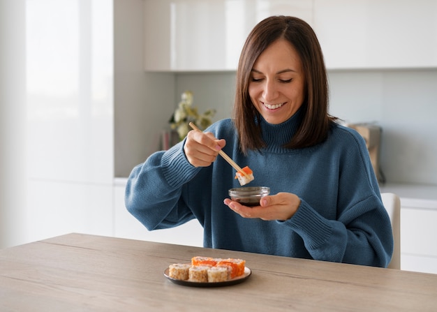 Middellange shot vrouw die thuis sushi eet