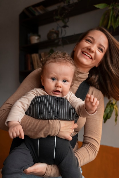 Gratis foto middellange shot vrouw met baby in draagzak