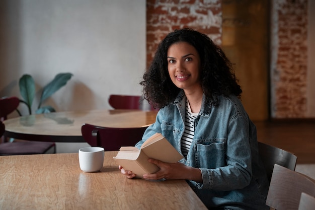 Gratis foto middellange shot vrouw met boek in coffeeshop