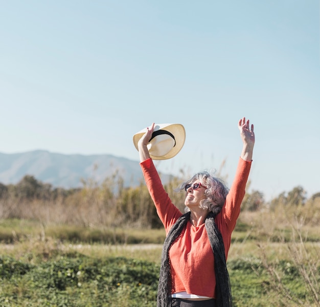 Gratis foto middellange shot vrouw met zonnebril en hoed