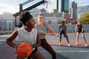 Gratis foto middellange shot vrouwelijke vrienden die basketbal spelen